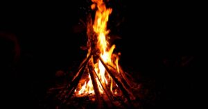 A vibrant campfire burning brightly at night, surrounded by logs and darkness.